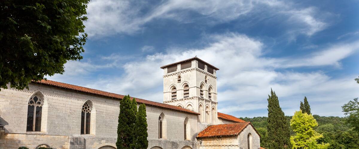 A historic church with a bell tower, surrounded by trees and a clear sky.