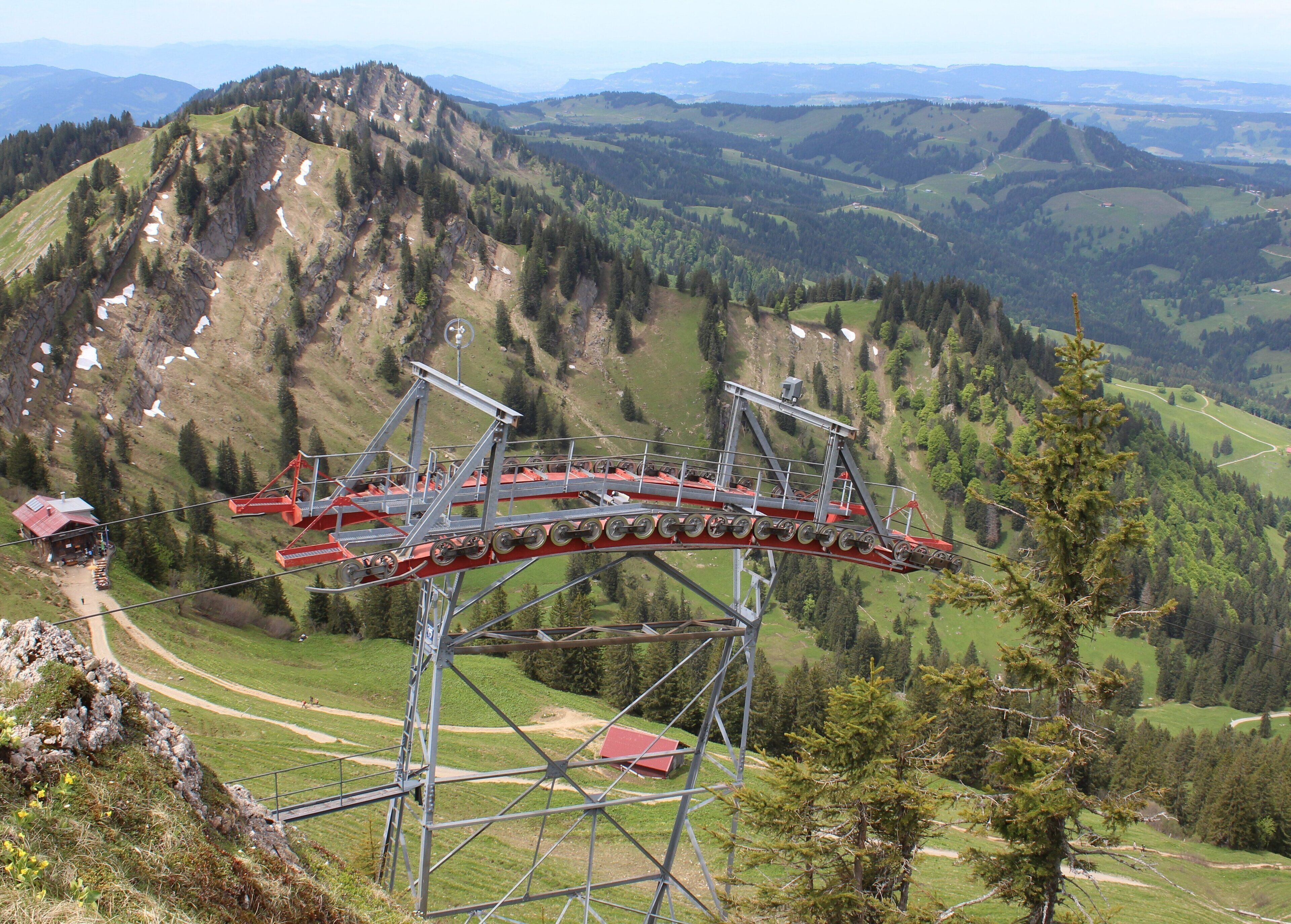 A cable car system in a mountainous area with green valleys and forested hills.