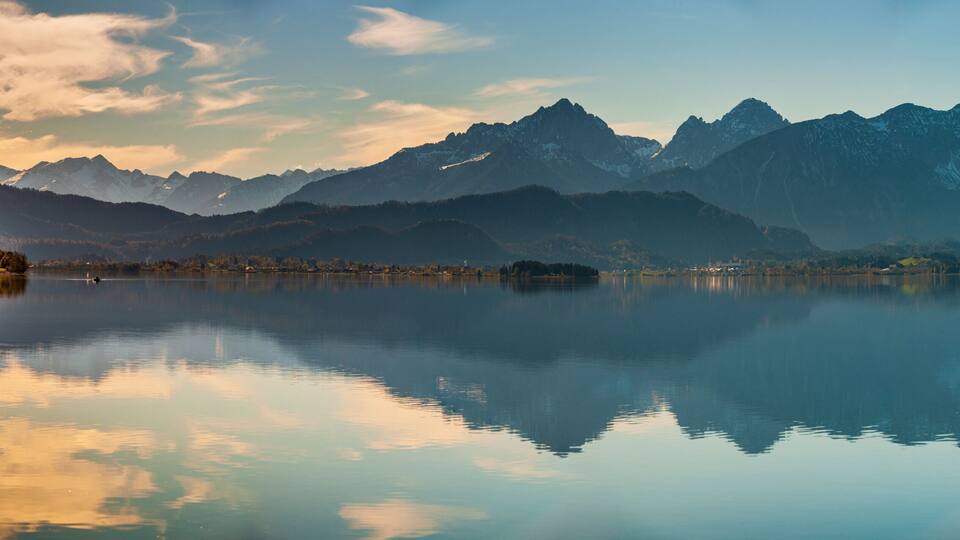 A calm lake reflecting mountains and trees.