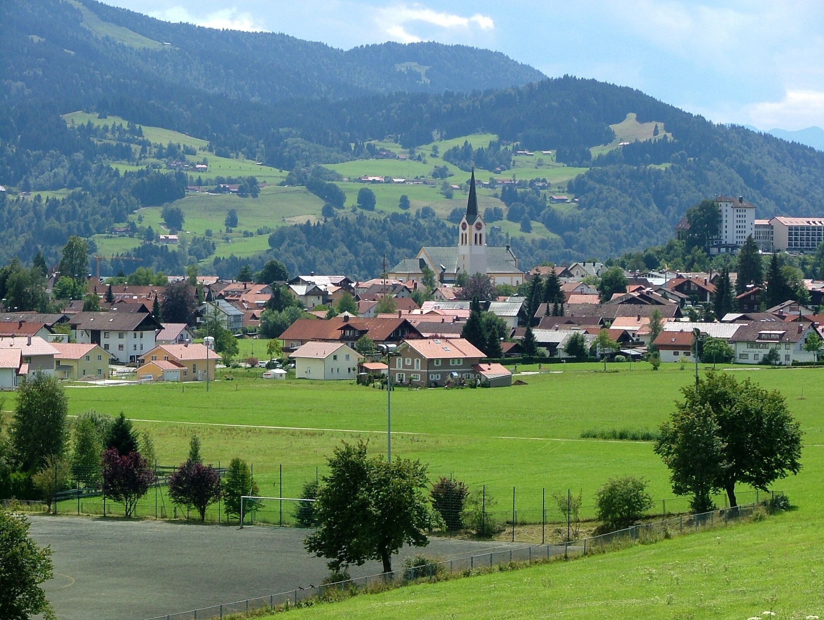 A town with a prominent church, surrounded by green fields and hills.