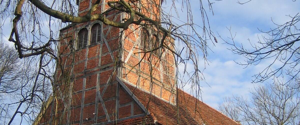 A historic church with a tall tower, stone walls, and a thatched roof.