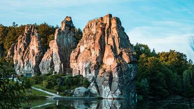 Isla rocosa con un reflejo nítido en aguas tranquilas, rodeada de vegetación.