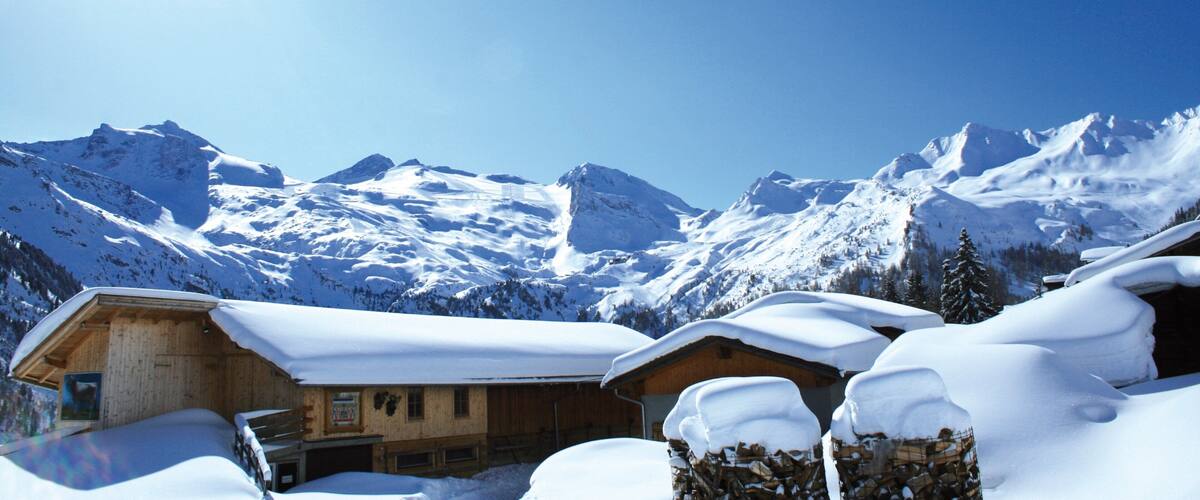 A snow-covered mountain landscape with wooden cabins and a clear blue sky.