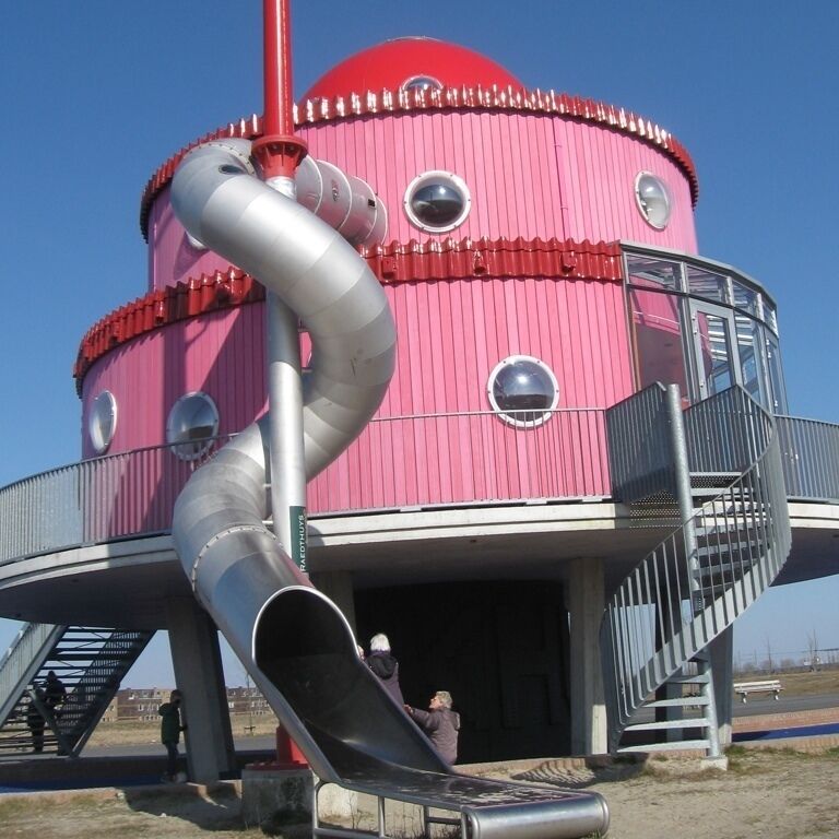 A pink cylindrical structure with a slide, stairs, and a metal staircase.