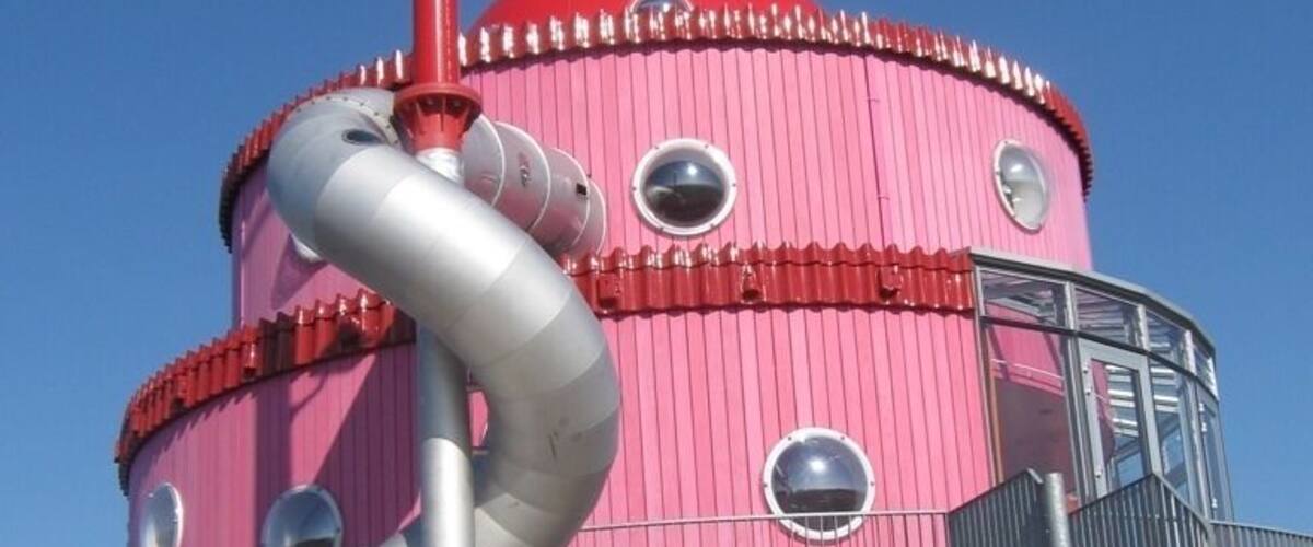 A pink cylindrical structure with a slide, stairs, and a metal staircase.