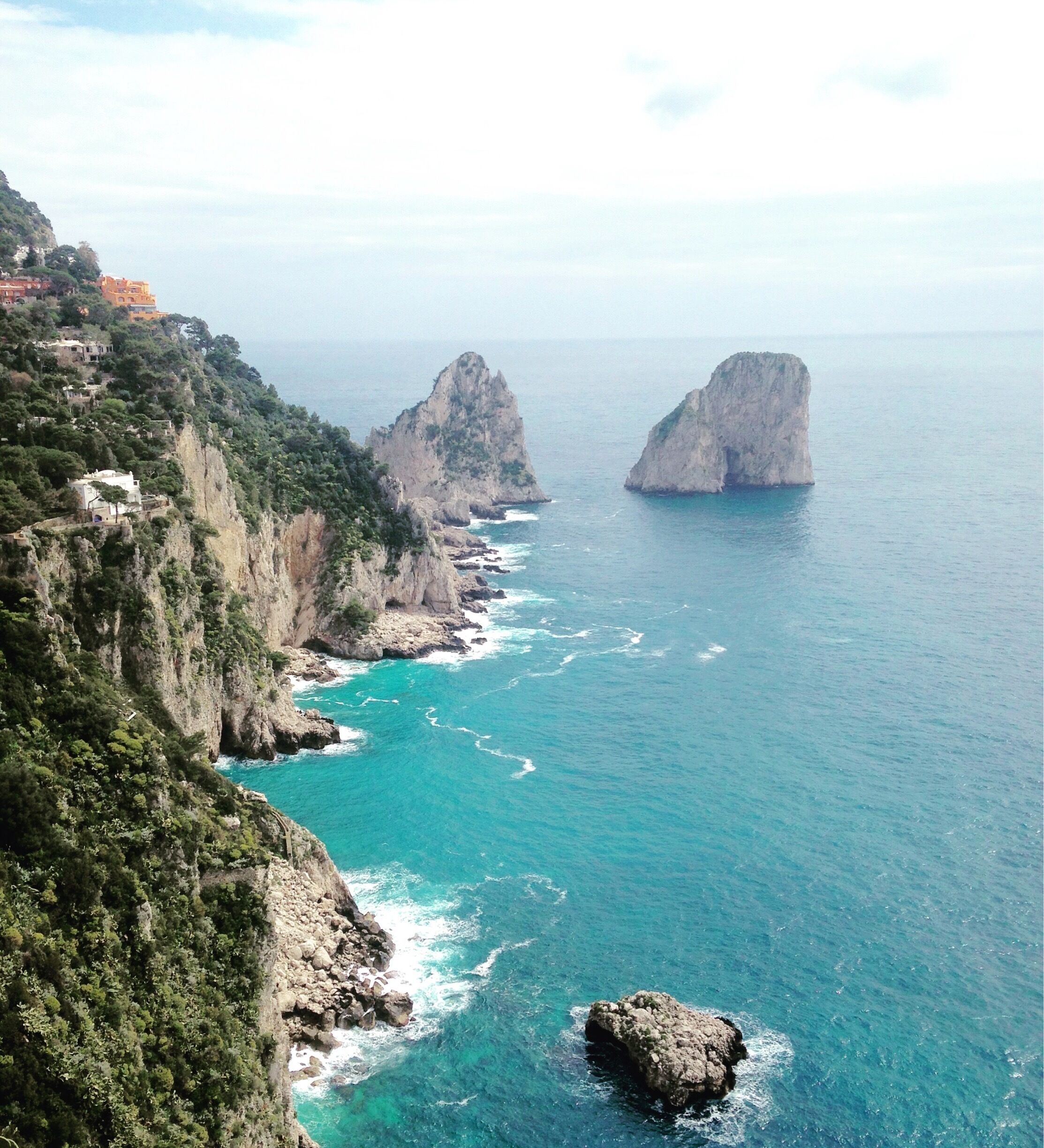 A coastal landscape with rocky cliffs and two prominent rock formations in the sea.