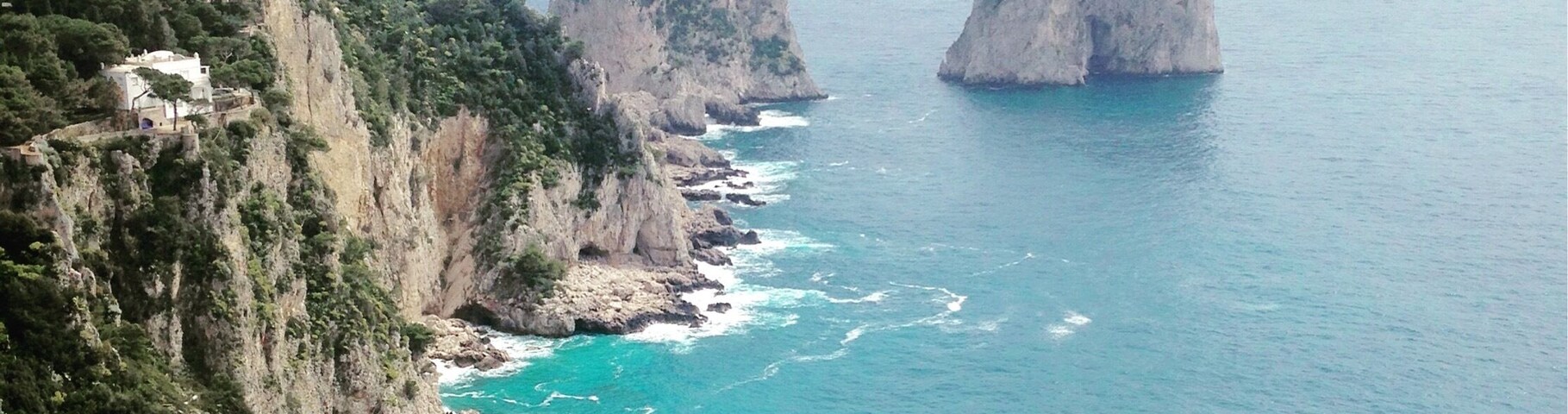 A coastal landscape with rocky cliffs and two prominent rock formations in the sea.