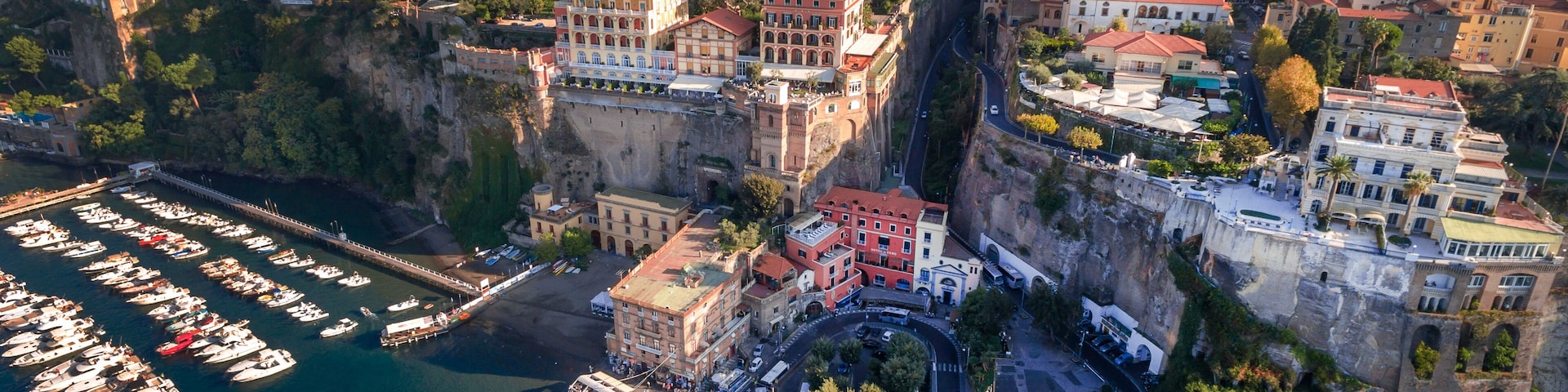 A coastal town with a marina, historic buildings, and a cliff overlooking the sea.