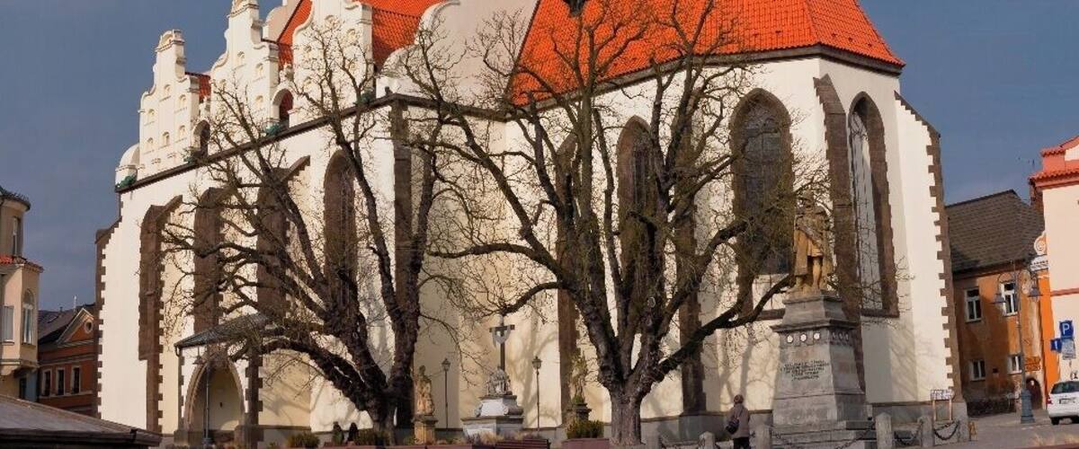 A historic church with a red roof and two towers, one with a green dome and the other with a clock.