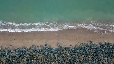 Aerial View of Waves Coming onto a Sandy Beach with Boulders - County Wicklow