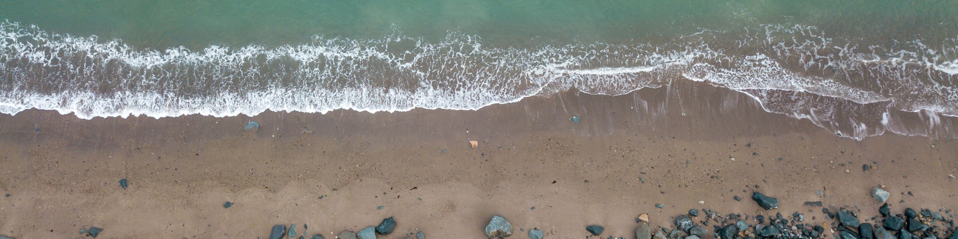 A beach with a rocky shoreline and waves approaching the shore.