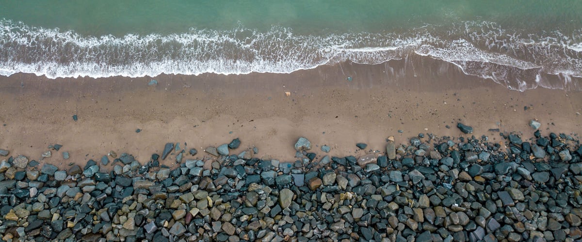 A beach with a rocky shoreline and waves approaching the shore.