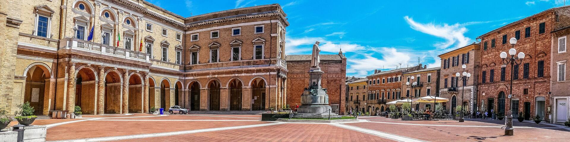 A historic square with classical architecture, a central statue, and surrounding buildings.