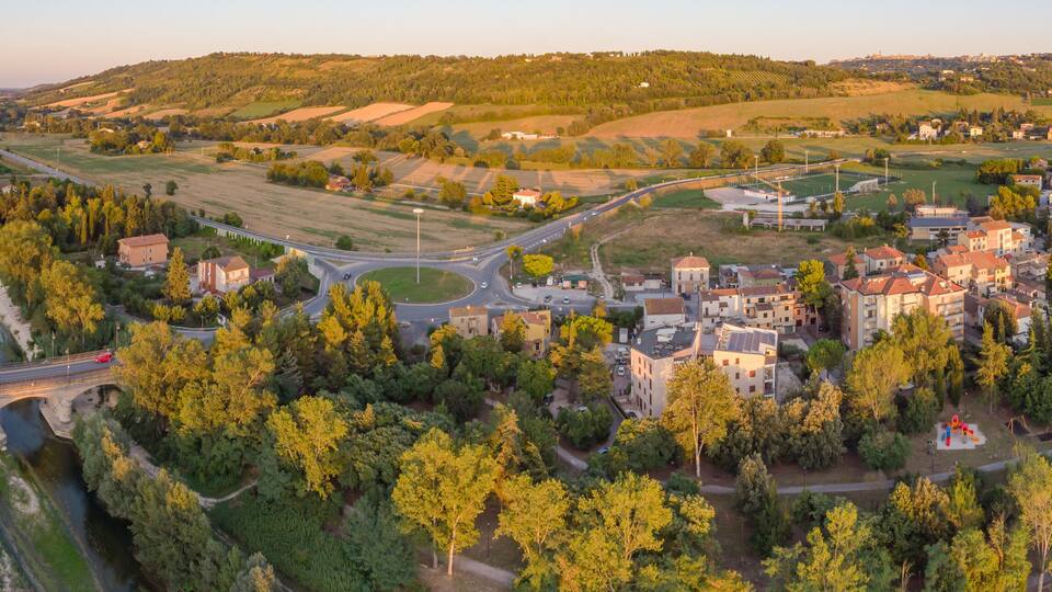 A town with a bridge over a river, surrounded by green fields and hills.