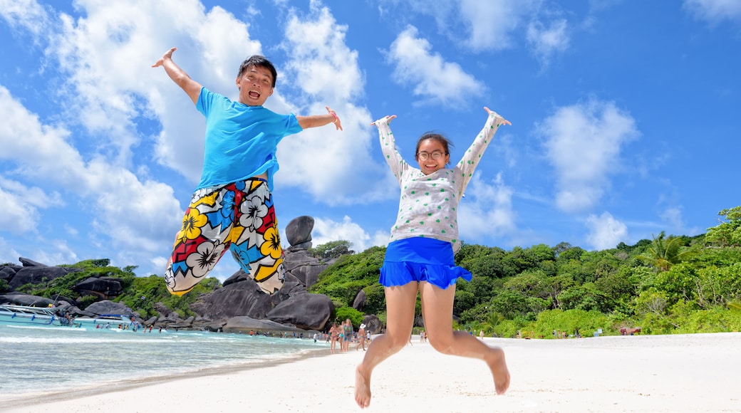 Father and daughter jumping with happy on beach near the sea under blue sky and cloud of summer at Koh Similan Island in Mu Ko Similan National Park, Phang Nga province, Thailand