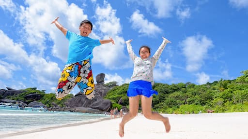 Father and daughter jumping with happy on beach near the sea under blue sky and cloud of summer at Koh Similan Island in Mu Ko Similan National Park, Phang Nga province, Thailand