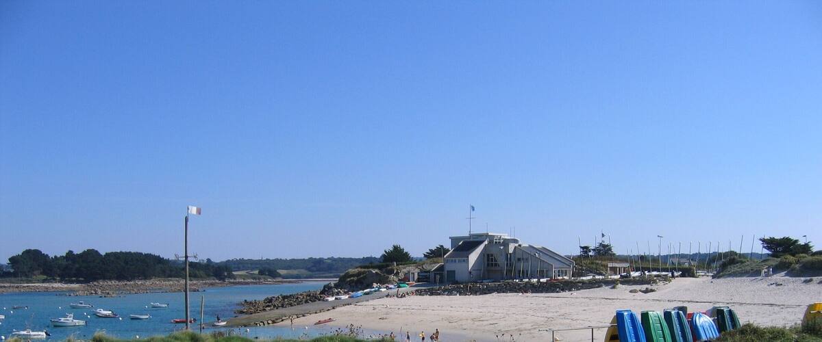 A beach with boats, a building, and a clear sky.