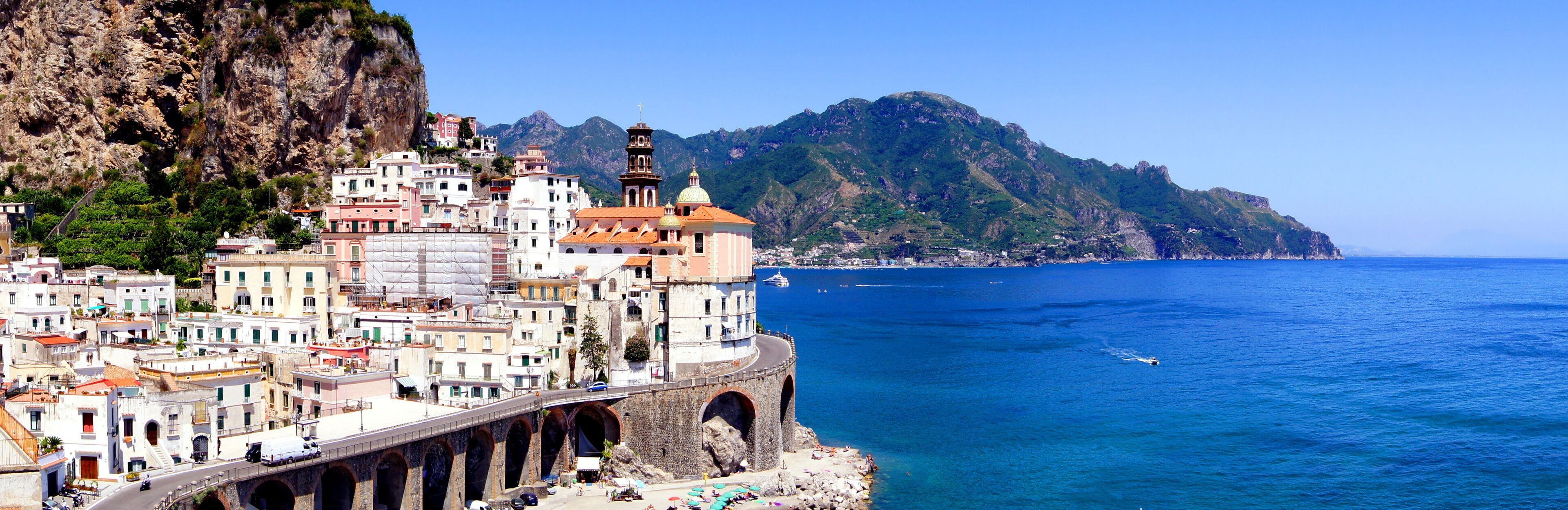 A coastal town with historic buildings, a prominent church, and a steep cliff overlooking the sea.