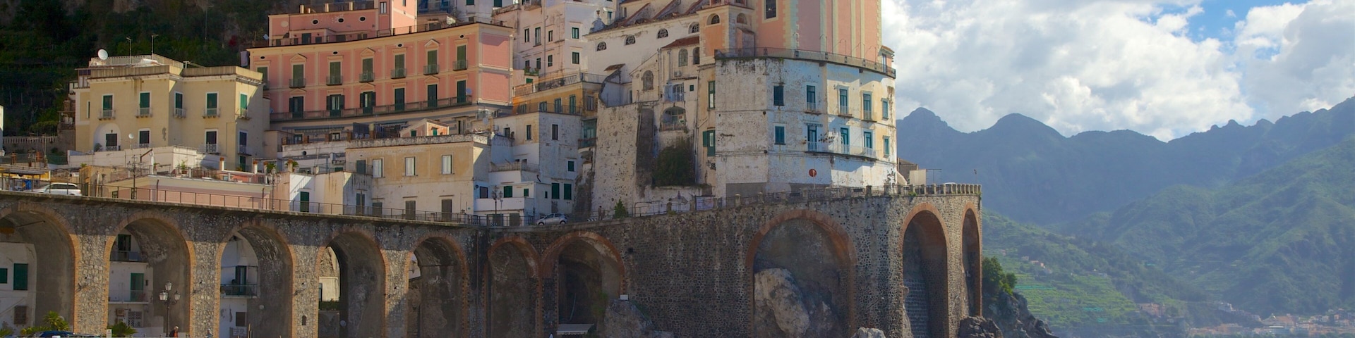 A coastal town with colorful buildings, a prominent church with a bell tower, and a beach with umbrellas.