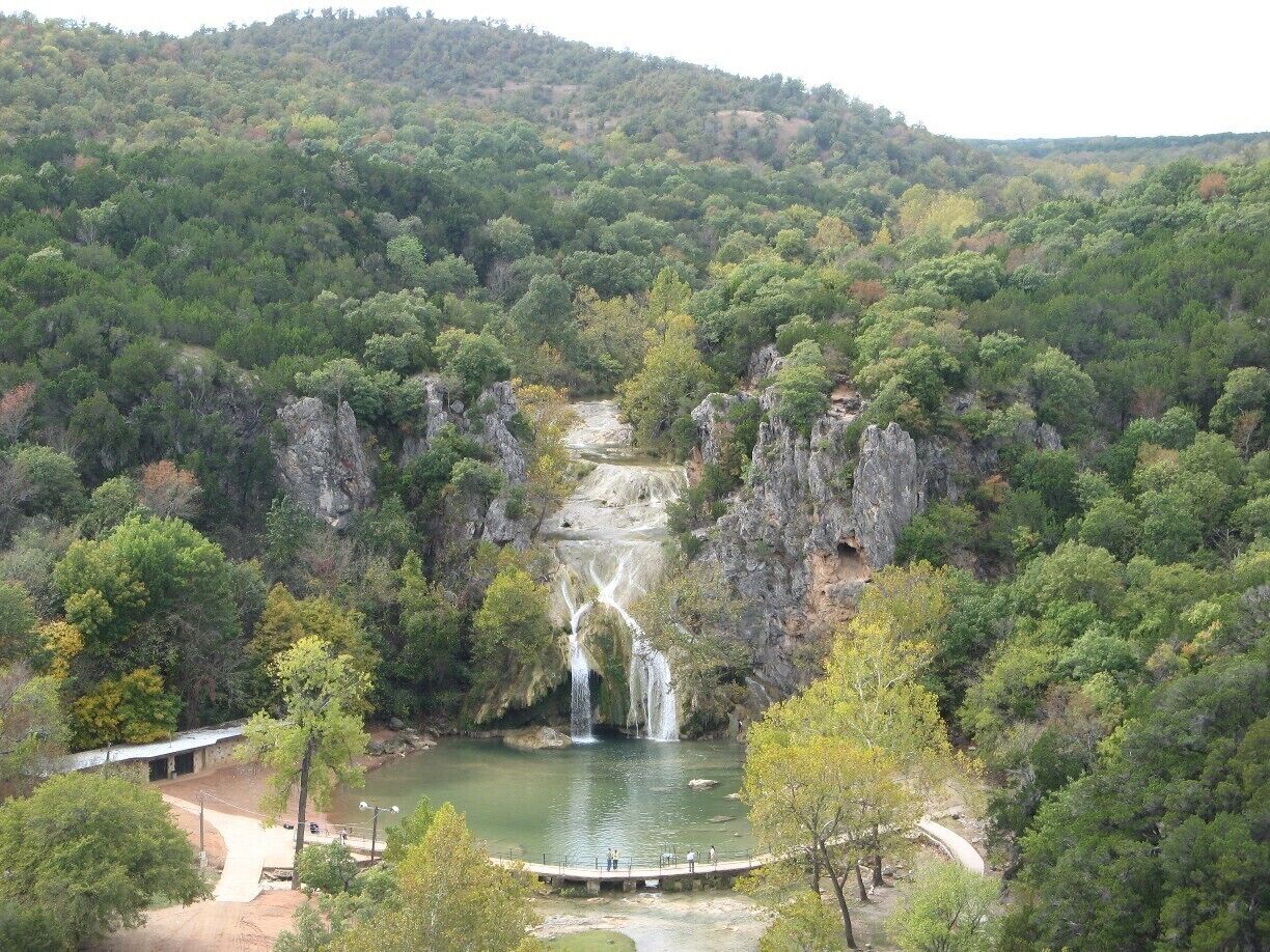 A waterfall cascading into a river surrounded by dense forest and rocky cliffs.