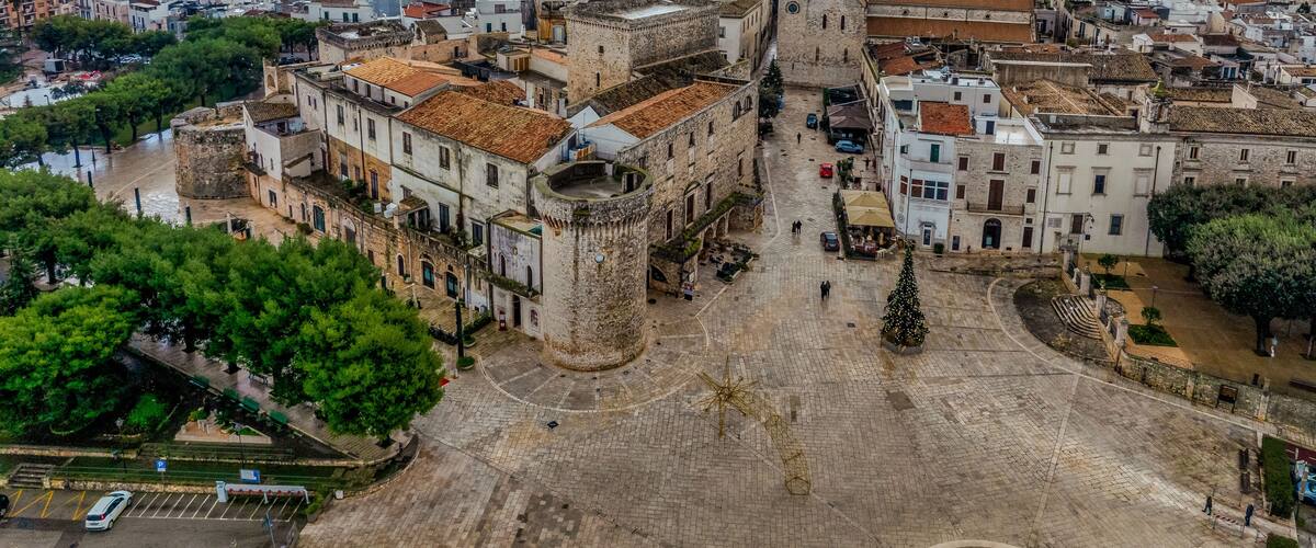 A historic town with a prominent tower, cobblestone streets, and a large open square.