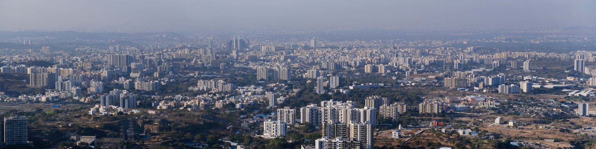 A densely populated urban area with numerous high-rise buildings and scattered green spaces.