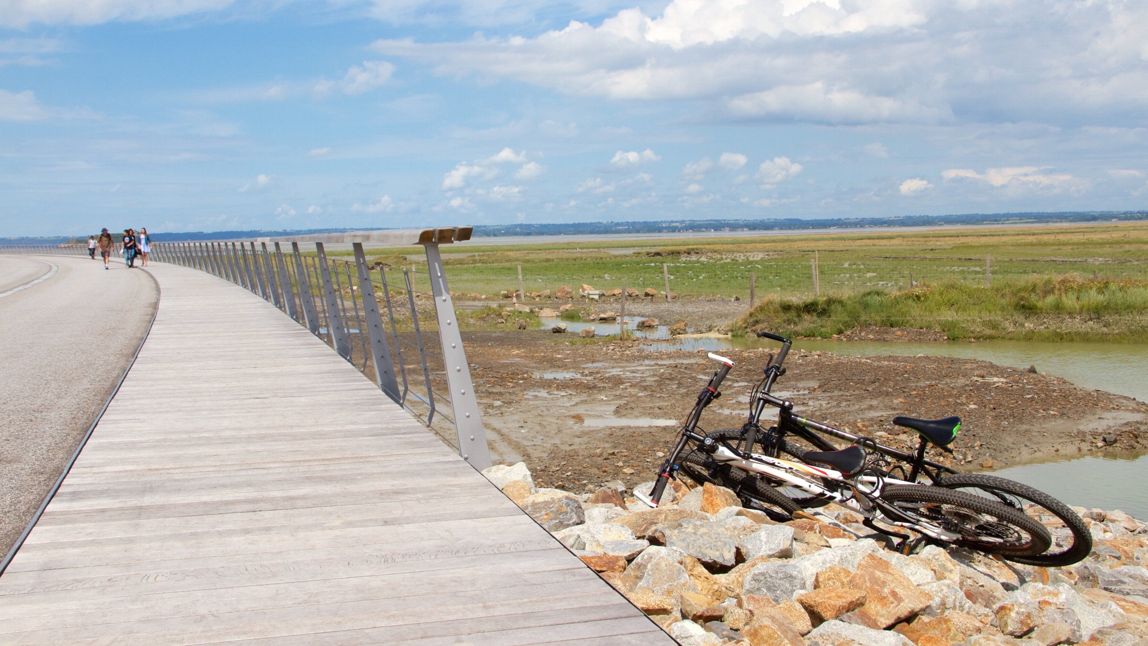 Un paseo marítimo de madera a lo largo de la orilla de un río, con bicicletas estacionadas sobre las rocas.