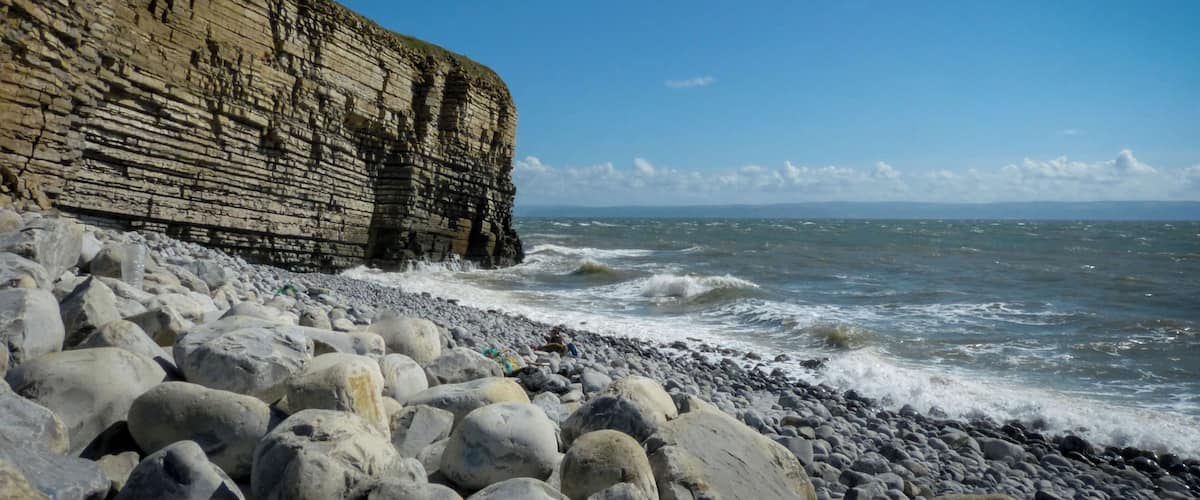 A rocky coastline with layered cliffs and waves crashing onto the shore.