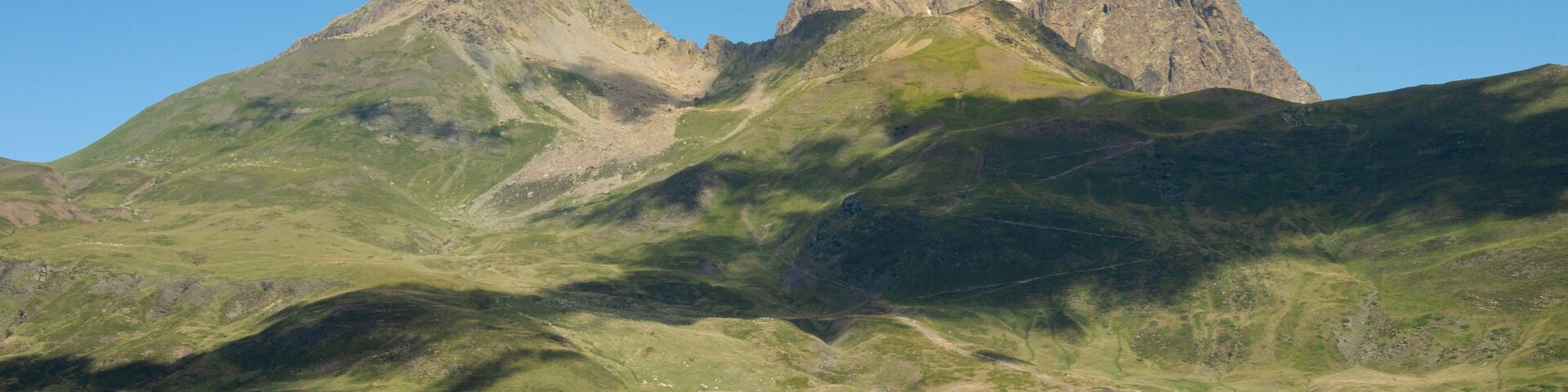 Paisagem montanhosa com dois picos distintos e um caminho sinuoso.