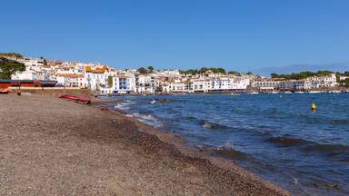 Pebble beach and waterfront houses in Cadaques on sunny day, Catalonia, Spain
