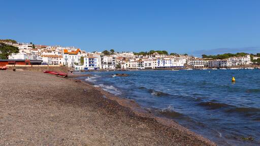 Pebble beach and waterfront houses in Cadaques on sunny day, Catalonia, Spain