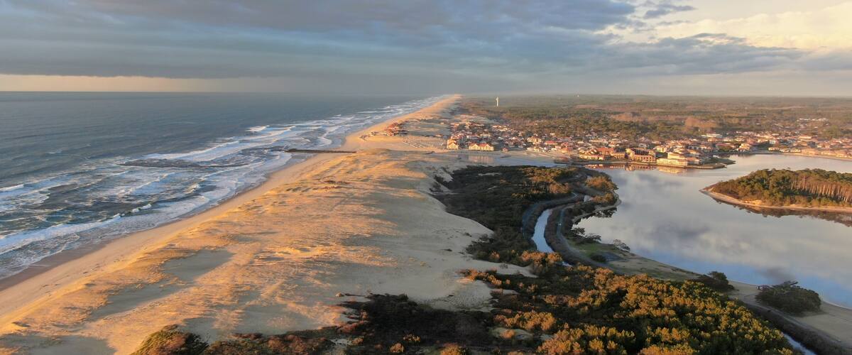 A coastal landscape with a beach, a winding river, and a town in the background.