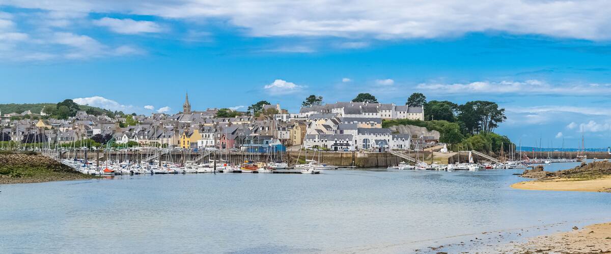 A coastal town with a marina, boats, and a prominent church spire.
