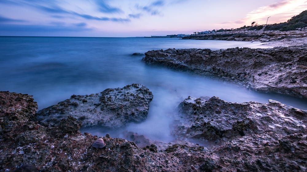 Un paysage côtier caractérisé par des formations rocheuses et une mer calme.