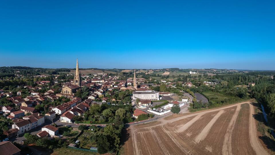 An aerial view of a town with a prominent church, residential areas, and agricultural fields.