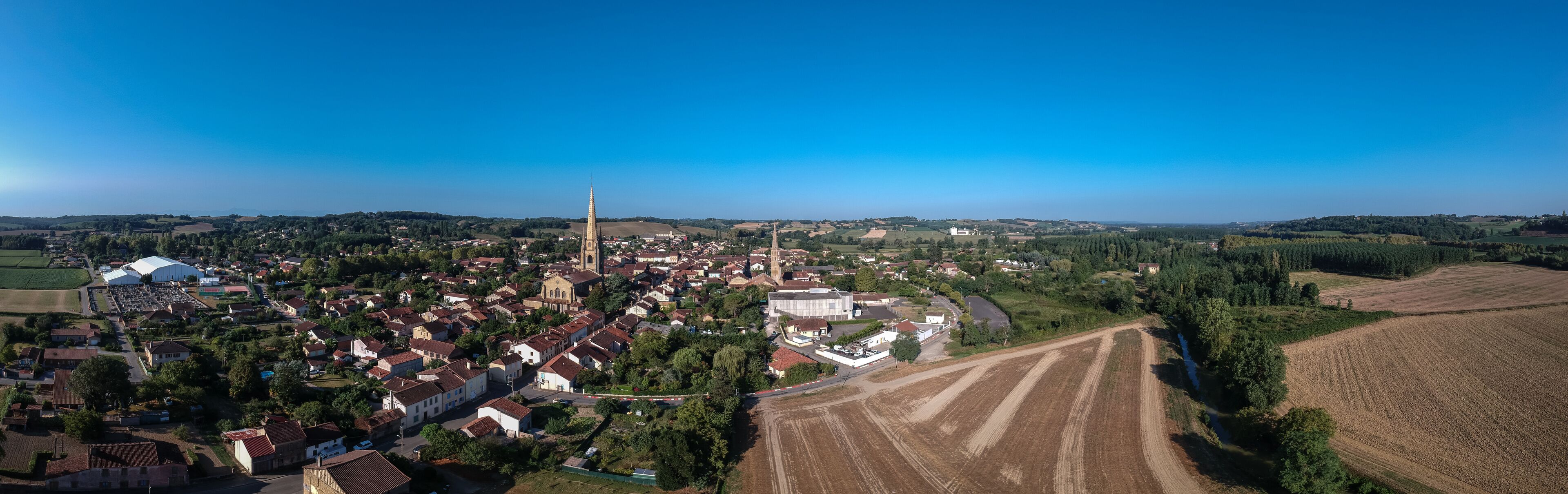An aerial view of a town with a prominent church, residential areas, and agricultural fields.