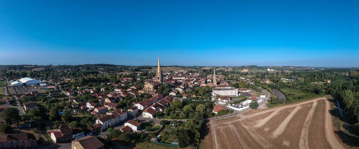 An aerial view of a town with a prominent church, residential areas, and agricultural fields.