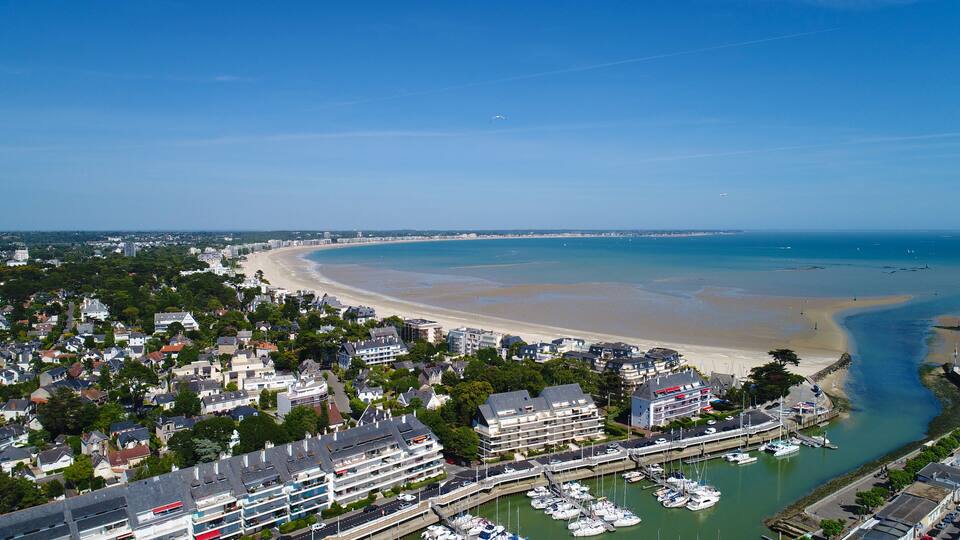 A coastal town with a beach, marina, and residential buildings.