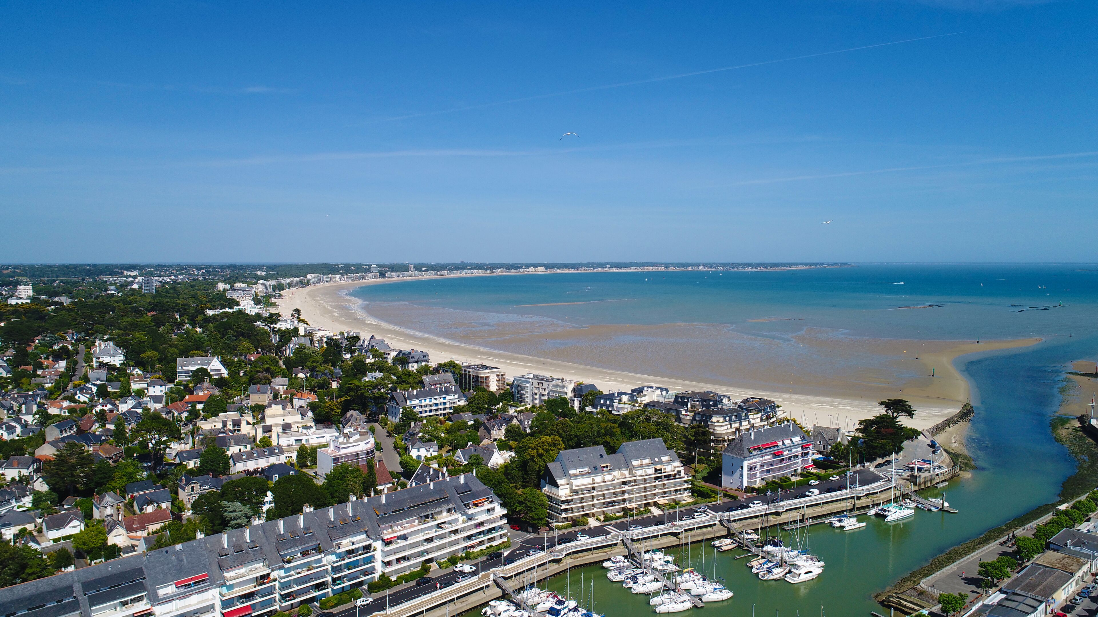 A coastal town with a beach, marina, and residential buildings.