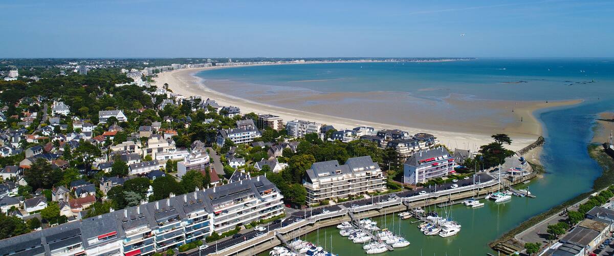 A coastal town with a beach, marina, and residential buildings.