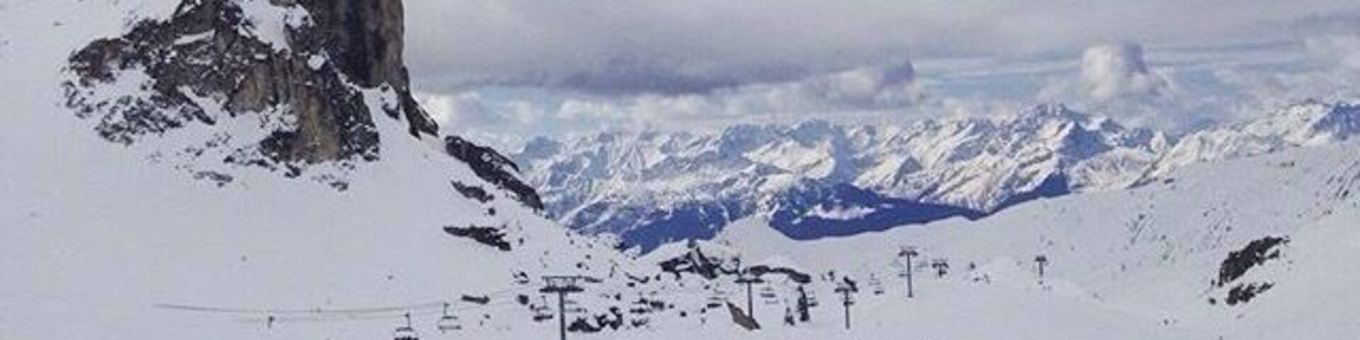 A snow-covered mountain with a rocky peak and ski slopes.