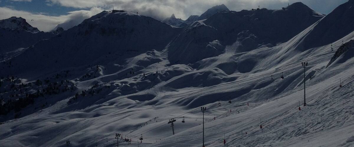 Un paysage de montagne enneigé, avec des remontées mécaniques et un ciel dégagé.