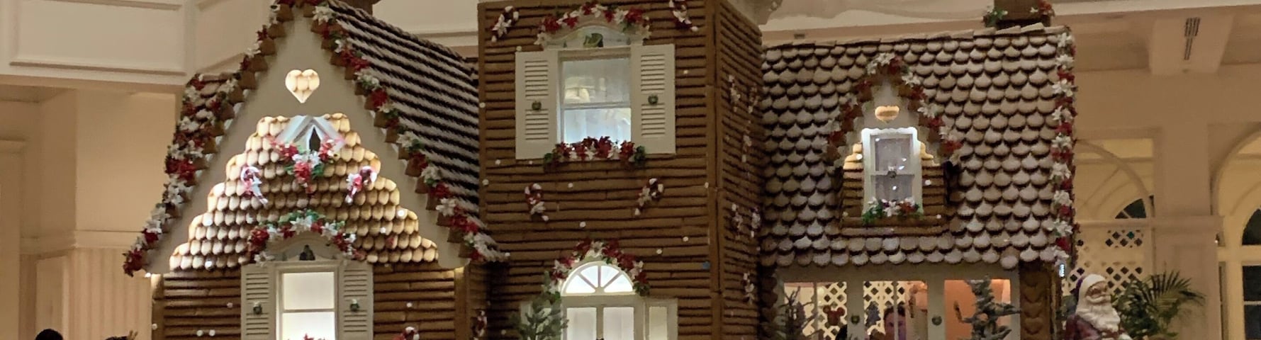 A gingerbread house display in a lobby with balconies and railings.