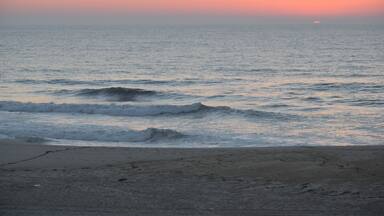 A beach with waves at sunset.
