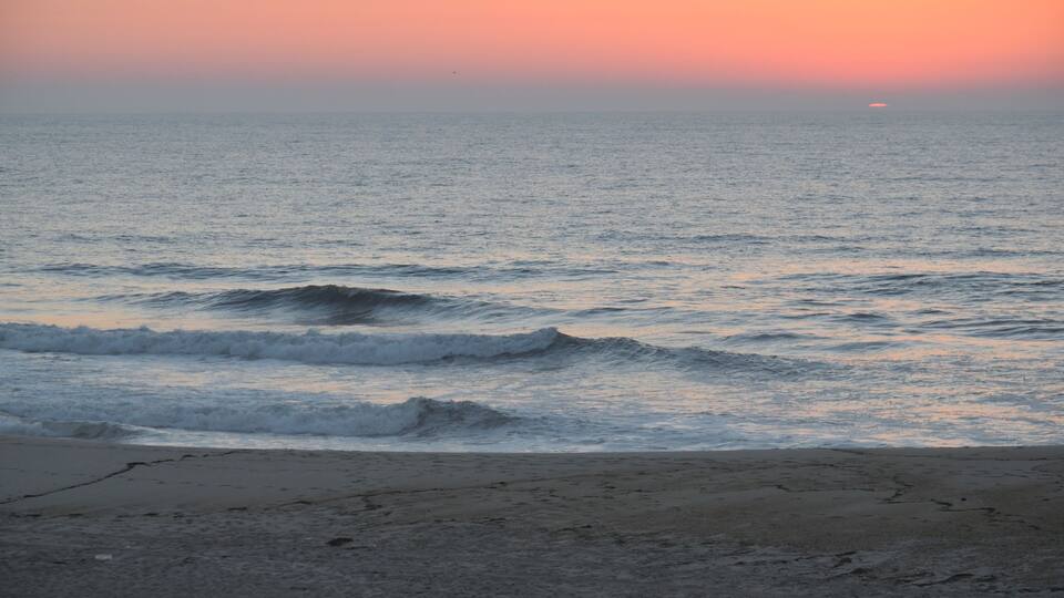 A beach with waves at sunset.