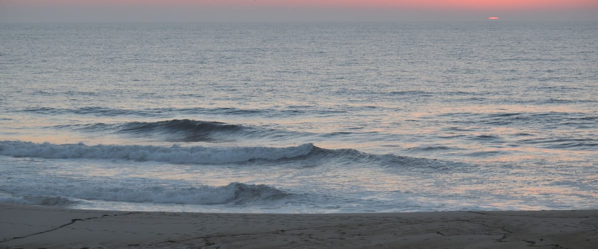 A beach with waves at sunset.