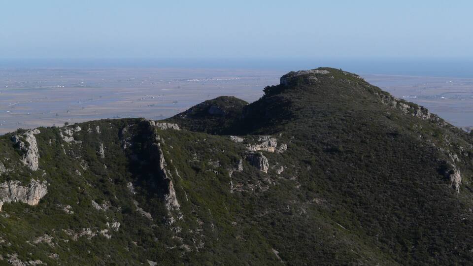 A mountainous landscape with a prominent peak and a valley in the background.