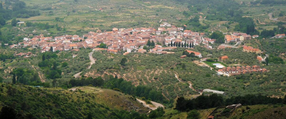 A town with red-roofed buildings nestled in a hilly, green landscape.