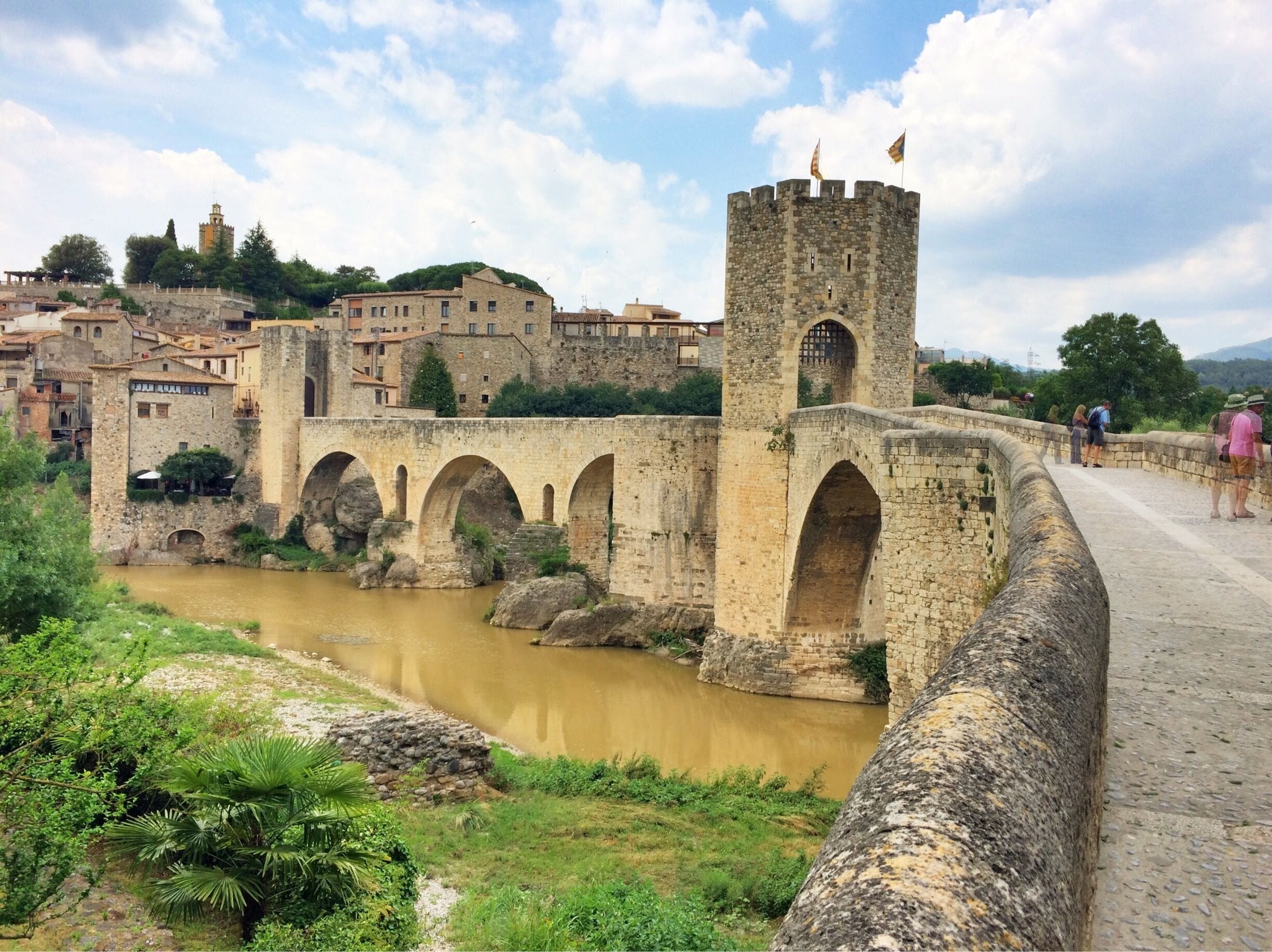 My oh my, Besalú. You sure charmed me. 

This tiny little hamlet is located northwest of Catalunya's biggest city, Girona, and public transport will you get you there in around an hour (for only €4.10 one way). 

The origins of this bridge are supposedly unknown, but its earliest mention of it in any sort of documentation was in the 11th century, with probably restorations in both the 14th and 20th century. 

I highly recommend taking a day trip here as I did, or even spending the night to see the city and especially the bridge light up.  You won't be disappointed. 