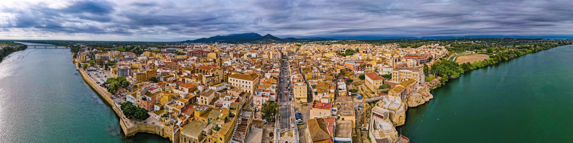 Uma cidade costeira com rio, edifícios históricos e uma ponte.